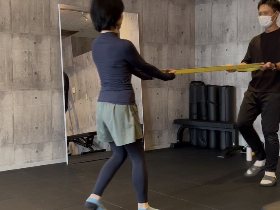 トレーナーと一緒にバンドを使った動きに取り組むグループレッスンの様子